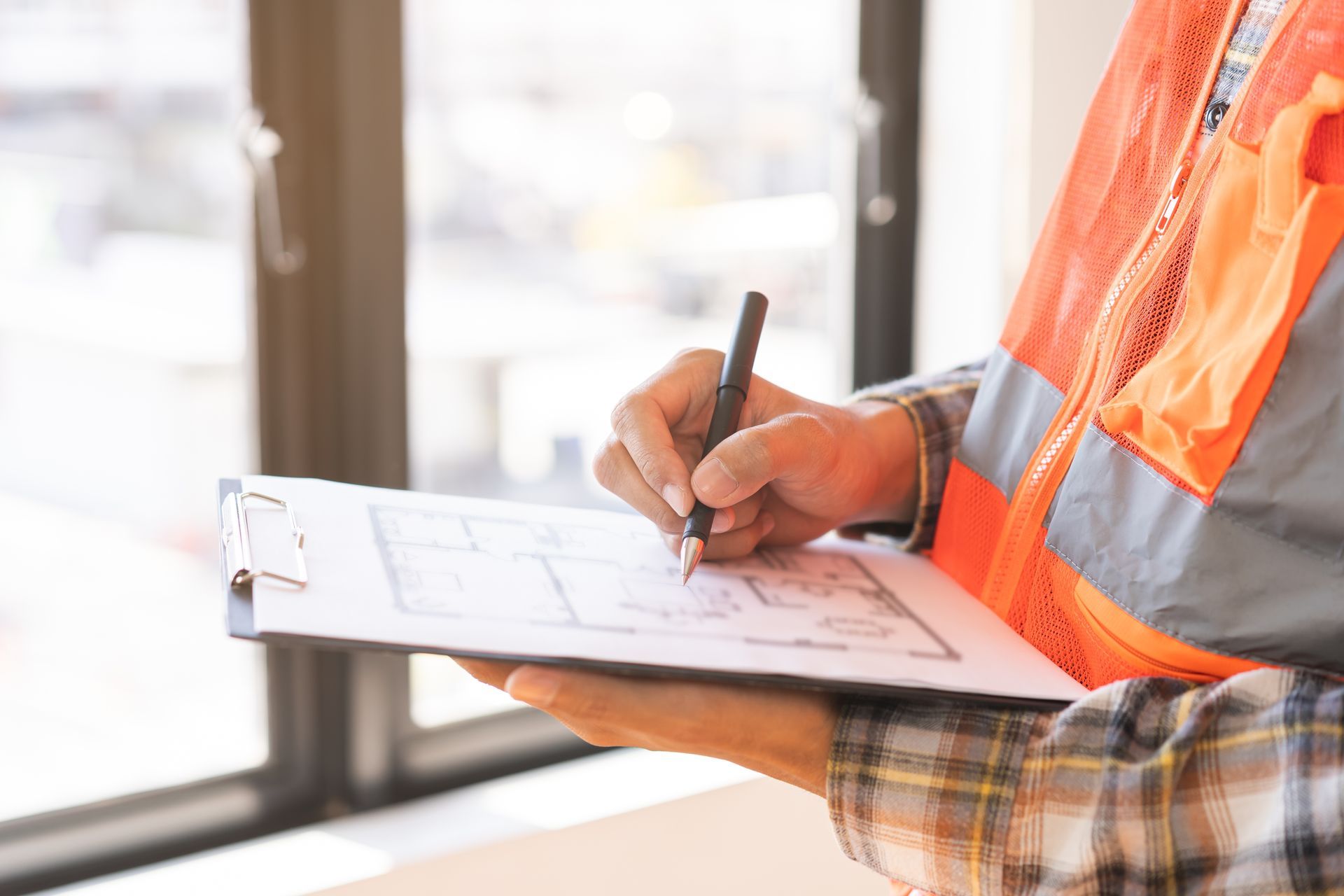 A construction worker is writing on a clipboard with a pen.