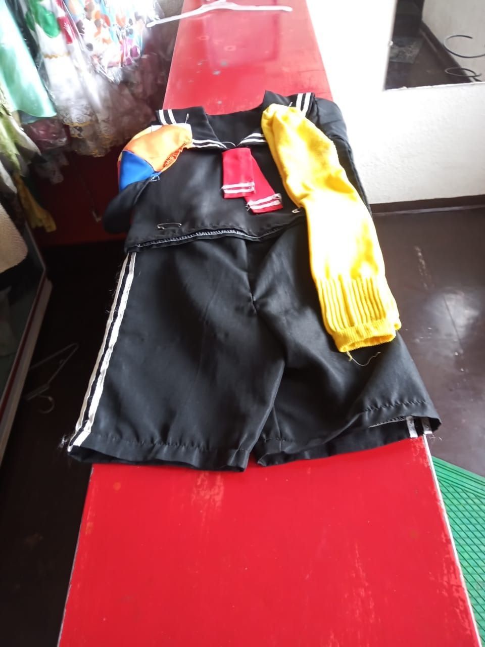 Una chaqueta negra y unos pantalones cortos están sobre una mesa roja.