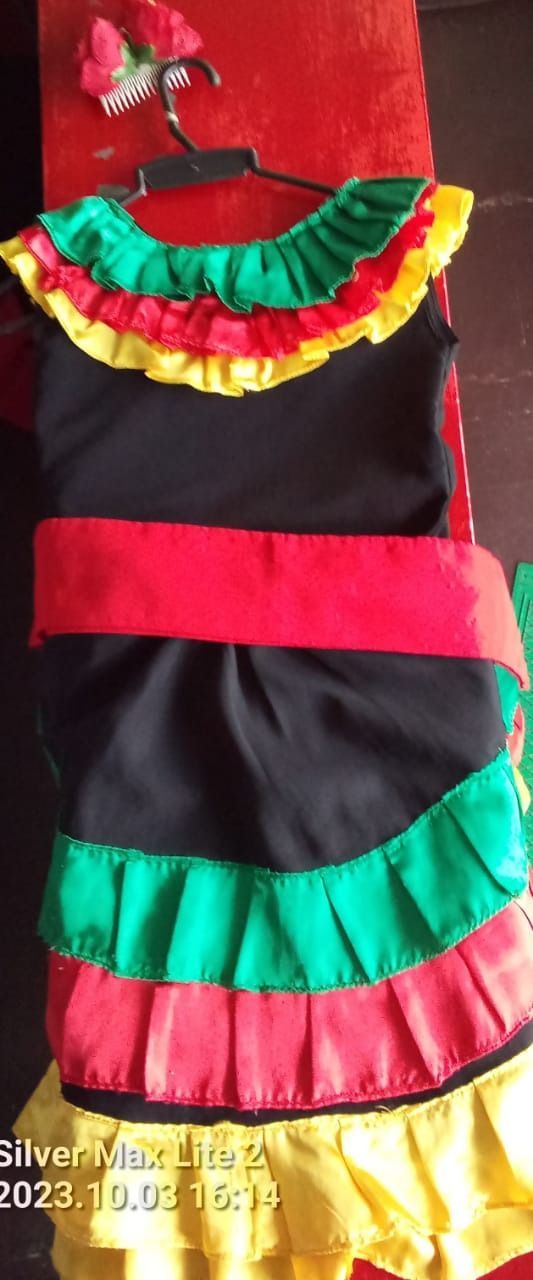 Un vestido colorido está colgado en una percha sobre una mesa roja.