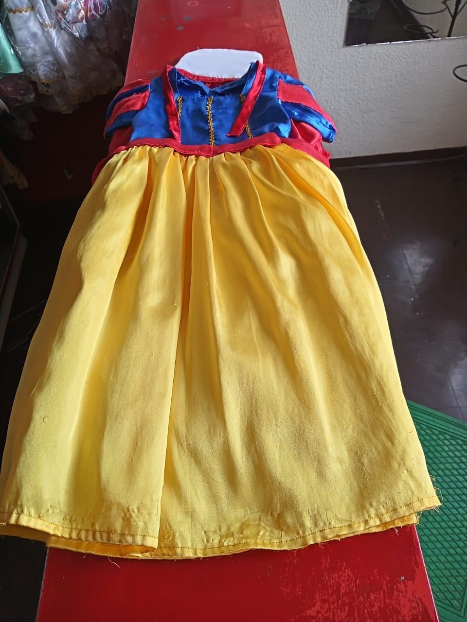 Un vestido blanco como la nieve está sobre una mesa roja.