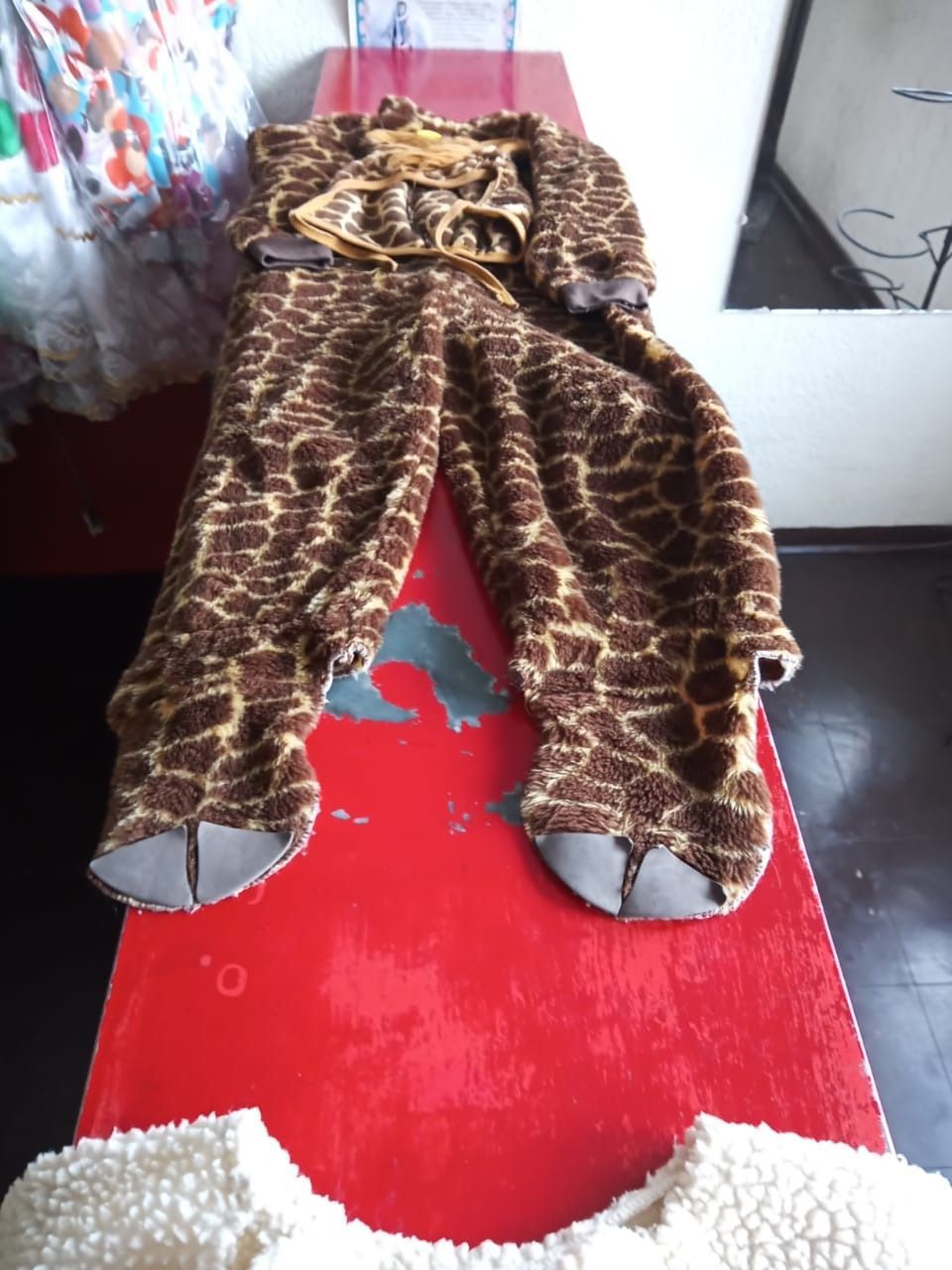 Un disfraz de jirafa está sobre una mesa roja.