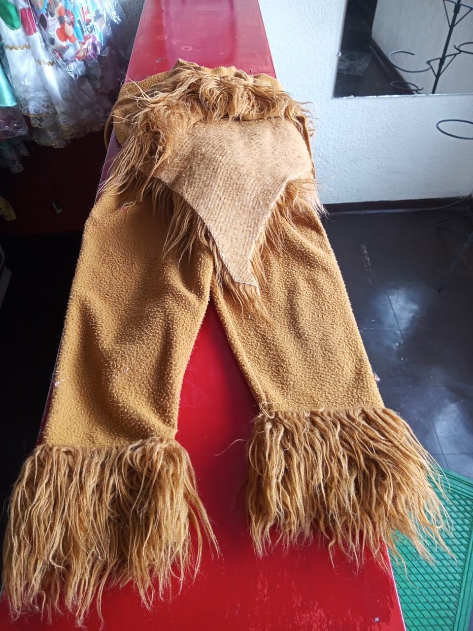 Un par de pantalones con plumas están sobre una mesa roja.