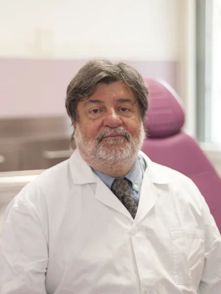 Un uomo con la barba e un camice bianco, probabilmente un medico, in uno studio medico.