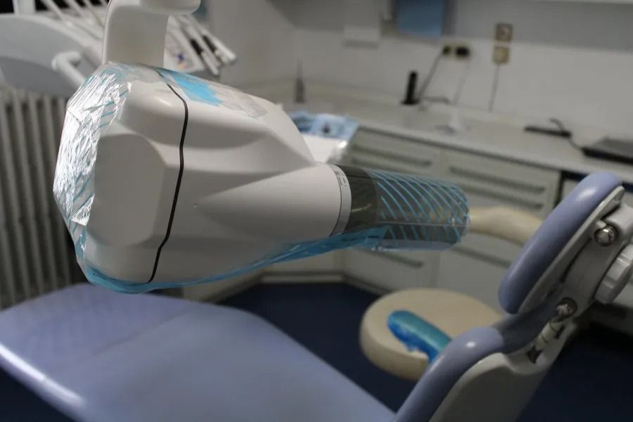 Poltrona odontoiatrica e lampada con copertura protettiva in uno studio dentistico.