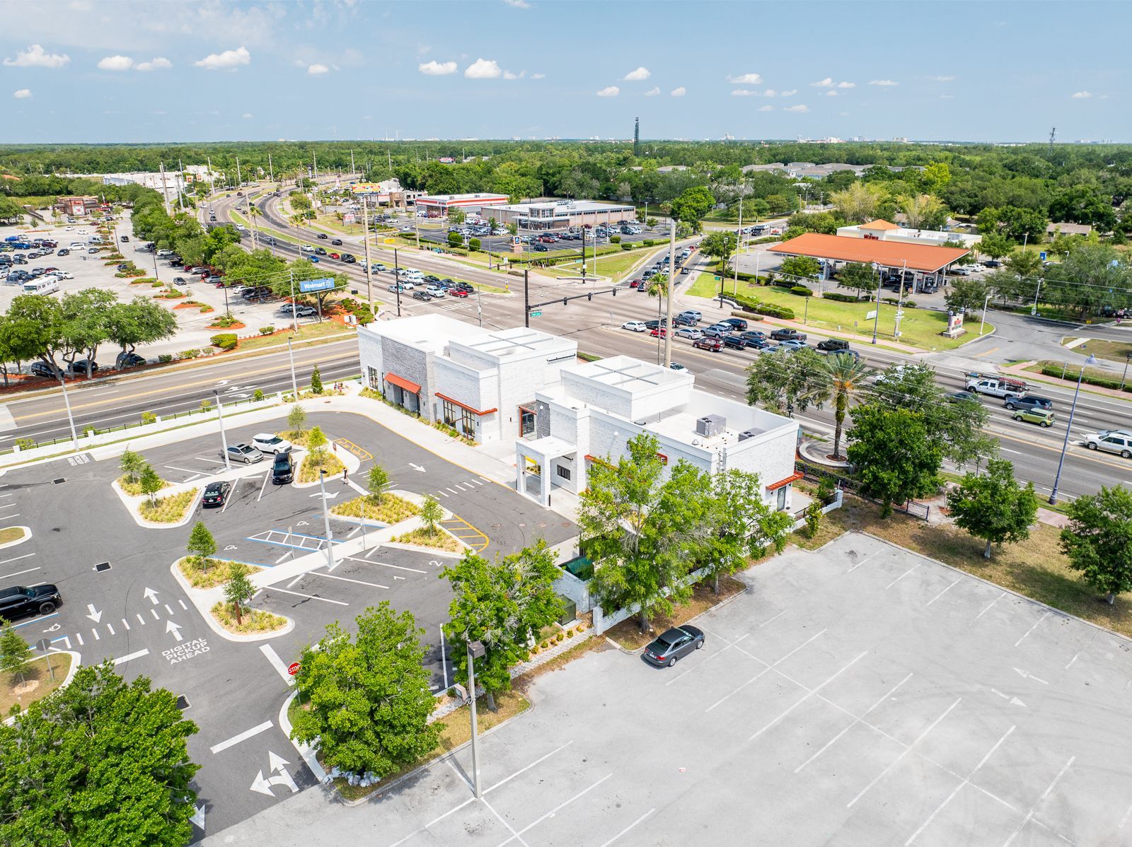 An aerial view of a parking lot with a building in the background.