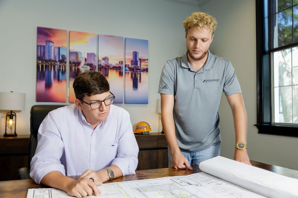 Two men are looking at a blueprint in an office.