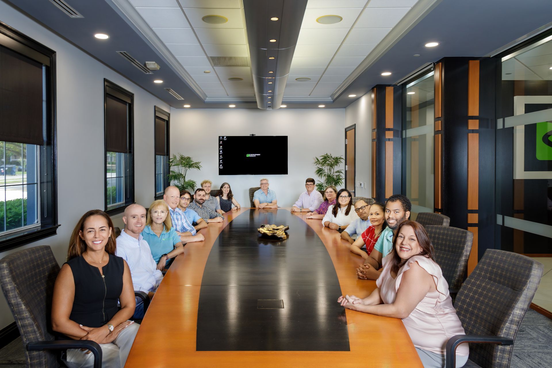 A group of people are sitting at a long table in a conference room.