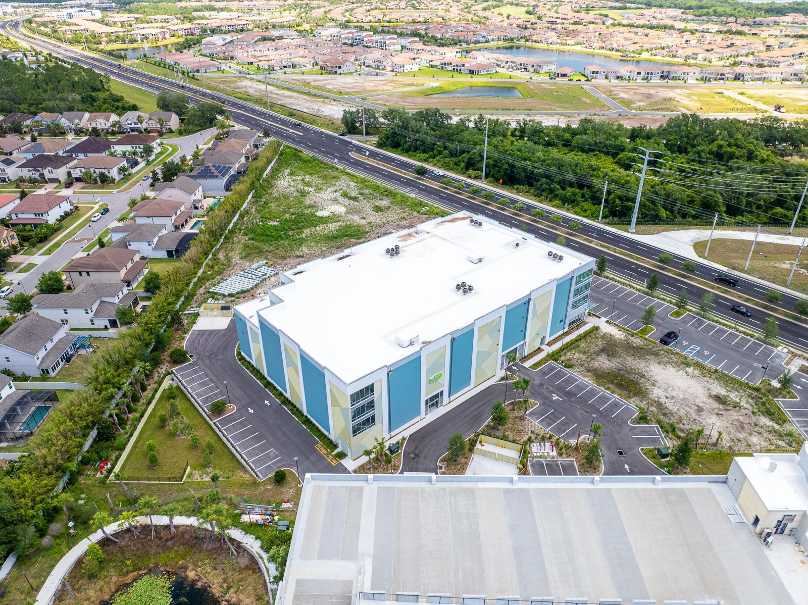 An aerial view of a large building with a white roof in a residential area.