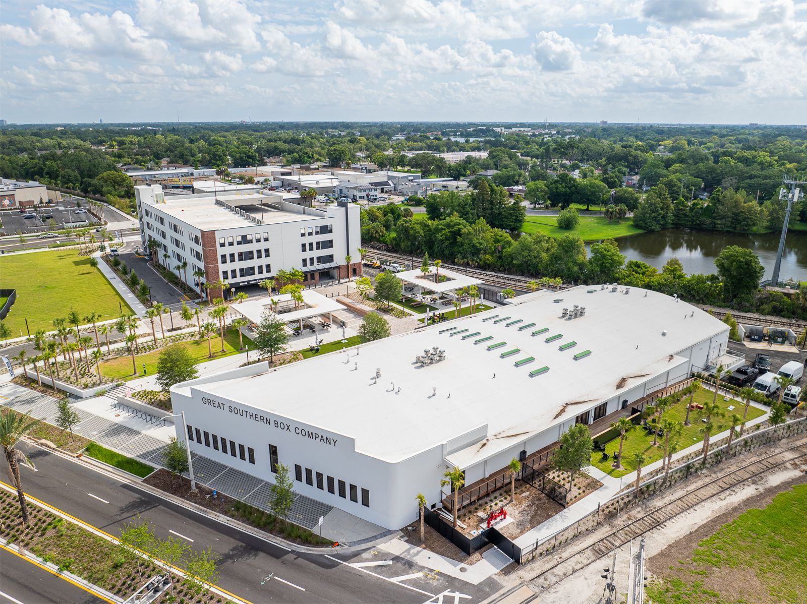 An aerial view of a large white building surrounded by trees and a river.