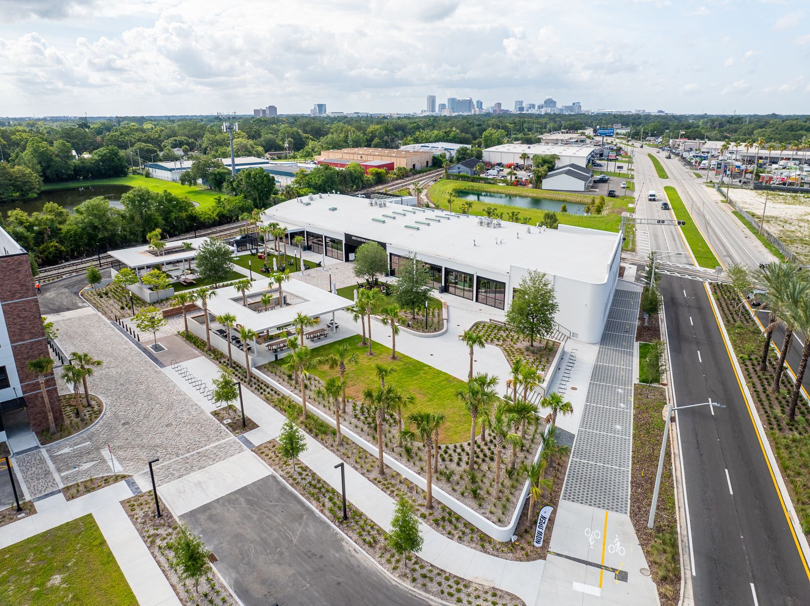 An aerial view of a large white building surrounded by trees and a road.