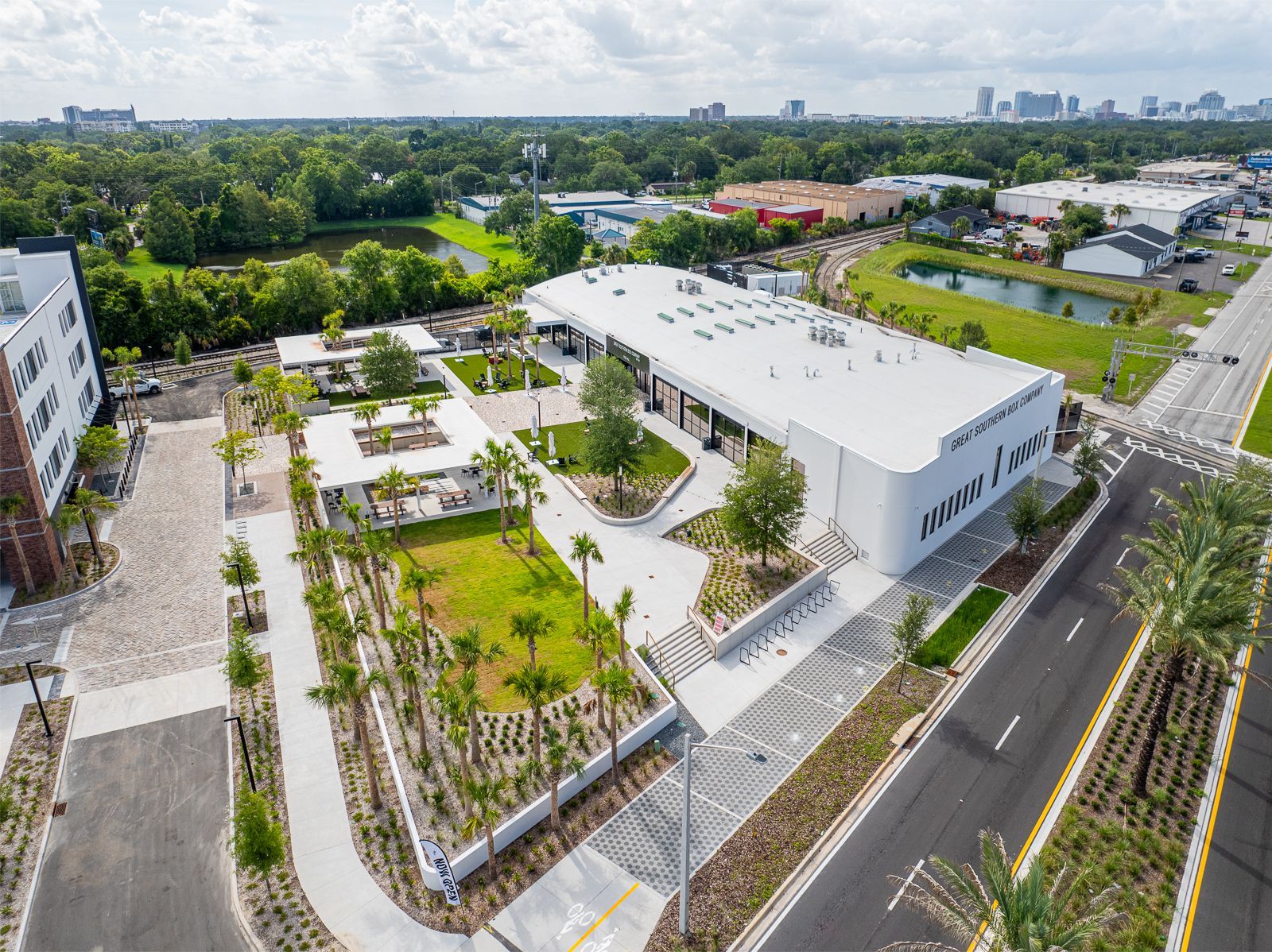 An aerial view of a large white building surrounded by trees and a road.