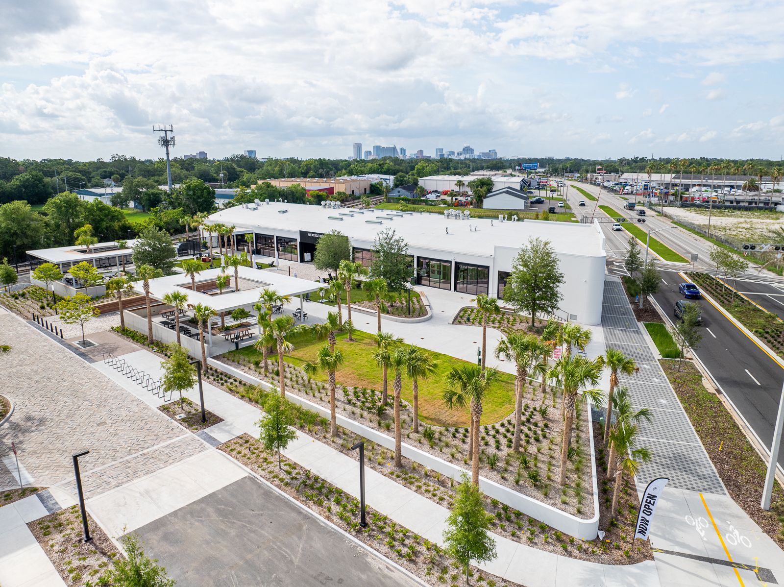 An aerial view of a large white building surrounded by trees and a road.