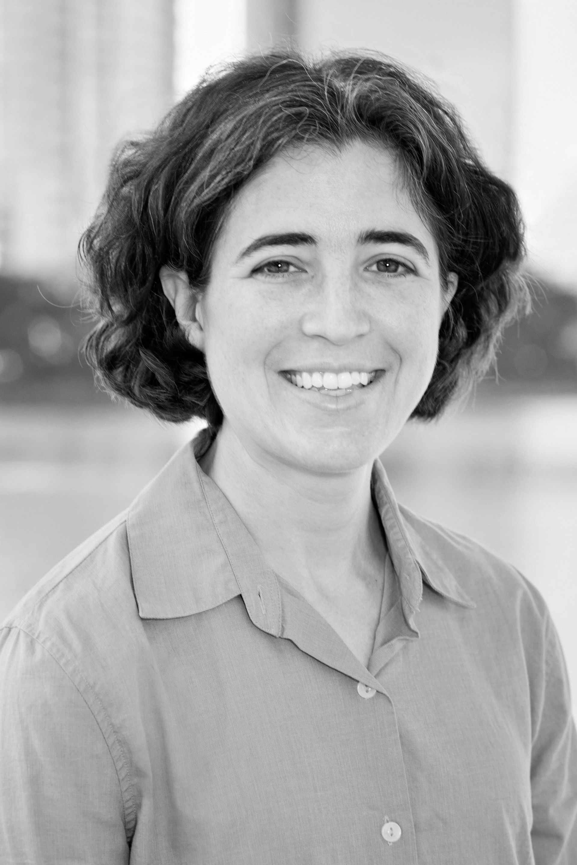 A black and white photo of a woman smiling for the camera.