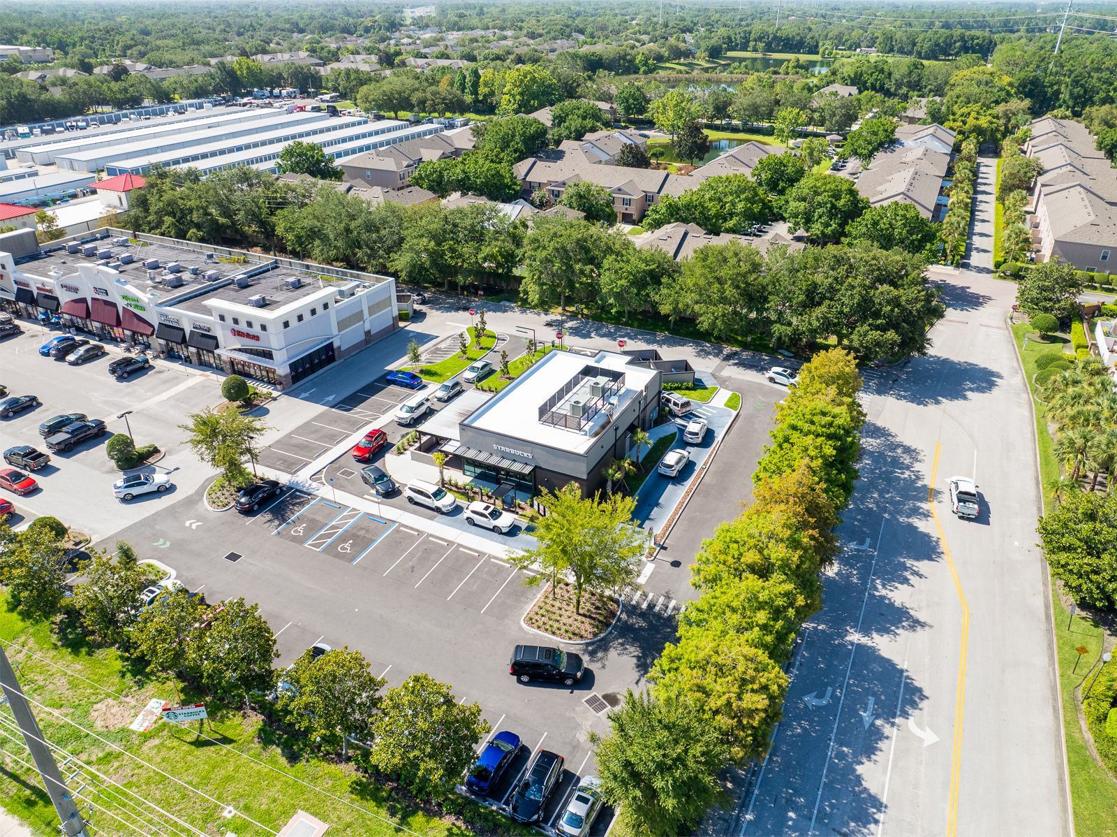 An aerial view of a parking lot with cars parked in front of a building.