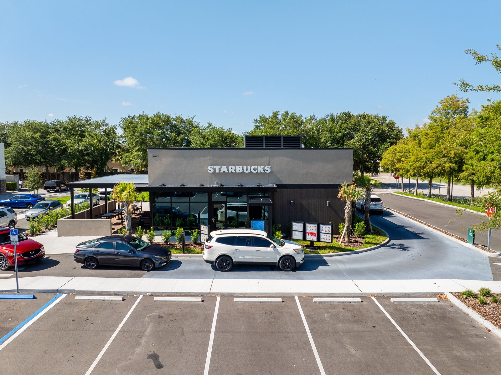 An aerial view of a starbucks coffee shop with cars parked in front of it