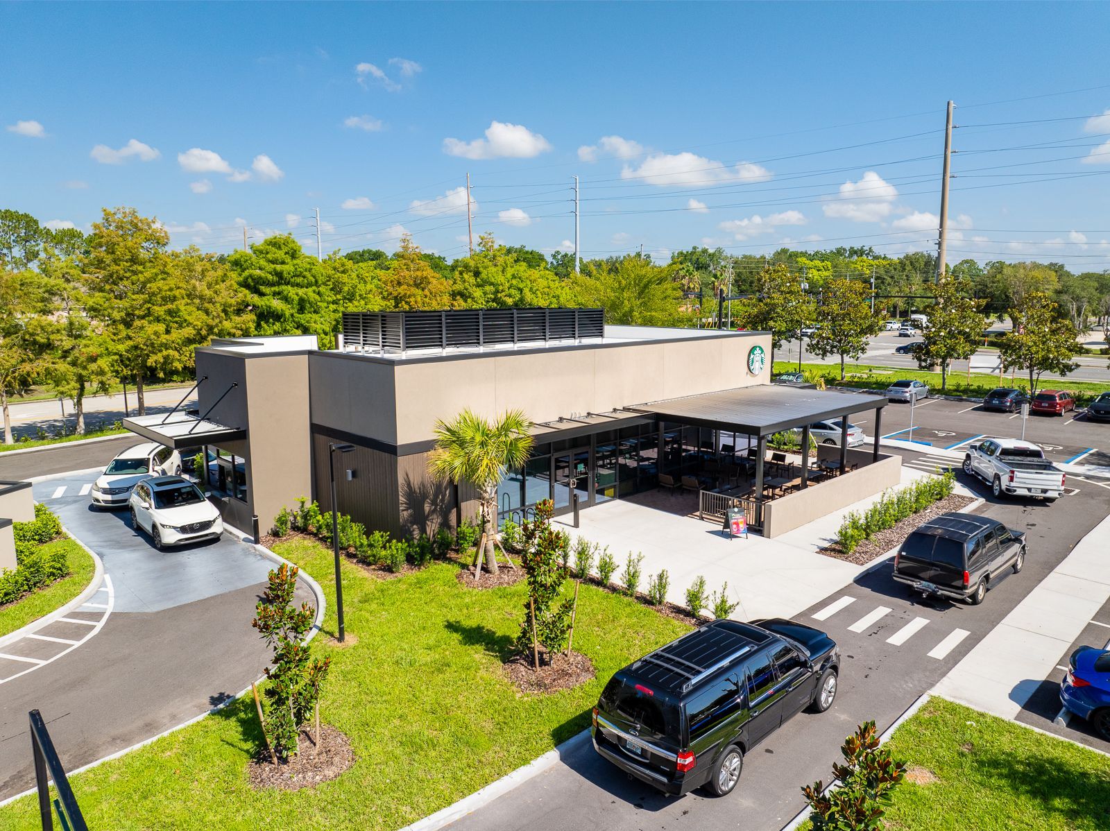 An aerial view of a starbucks coffee shop with cars parked in front of it.