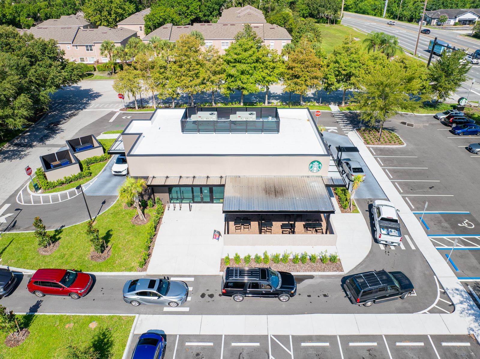 An aerial view of a starbucks coffee shop with cars parked in front of it.