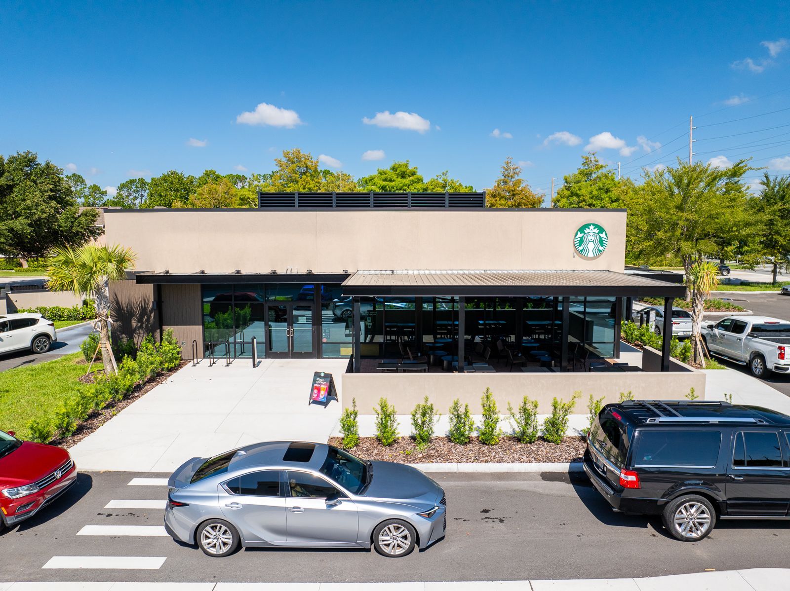 A starbucks coffee shop with cars parked in front of it
