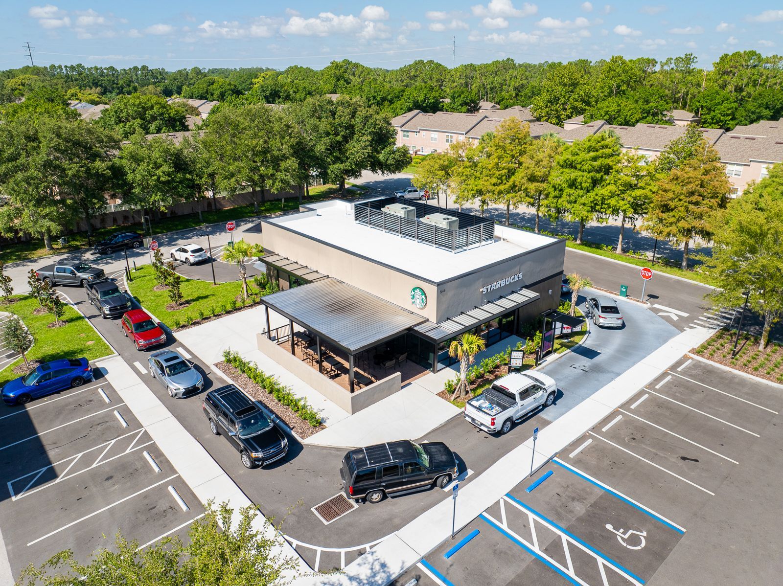 An aerial view of a starbucks coffee shop with cars parked in front of it.