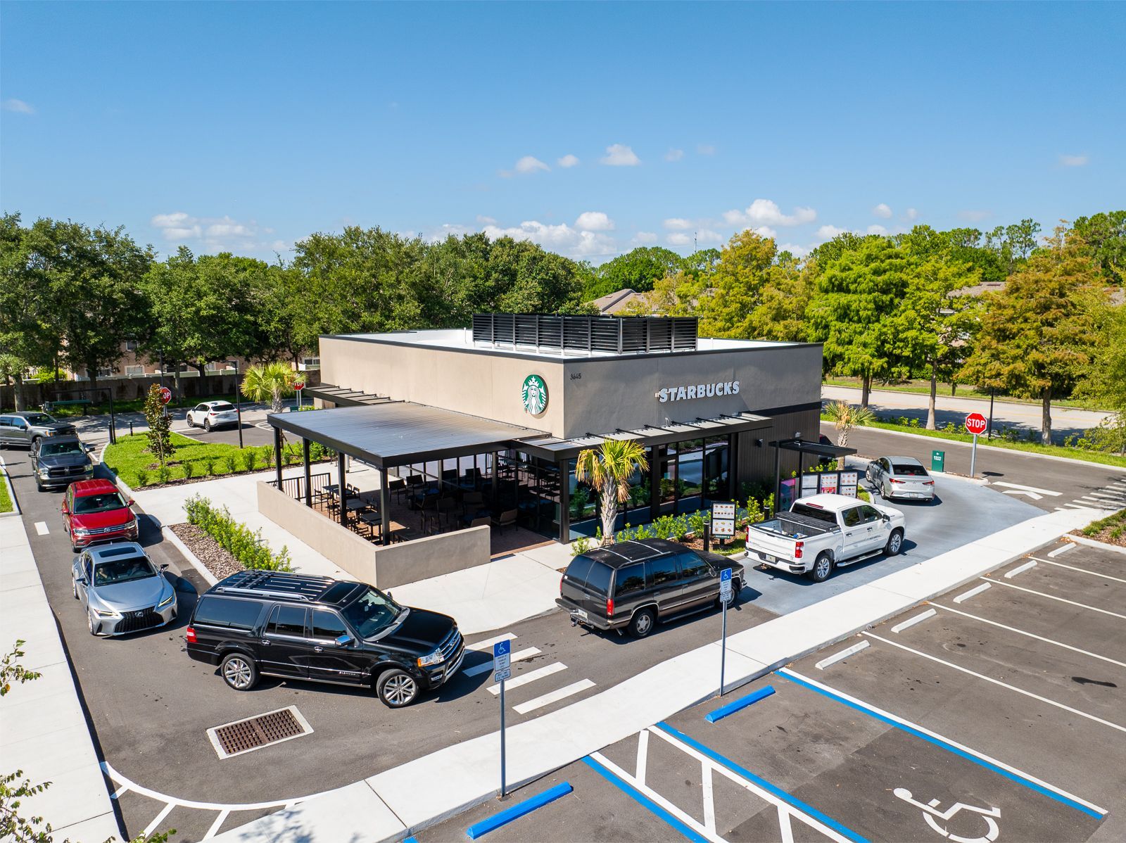 An aerial view of a starbucks coffee shop with cars parked in front of it