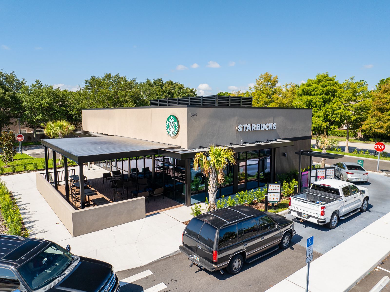 An aerial view of a starbucks coffee shop with cars parked in front of it