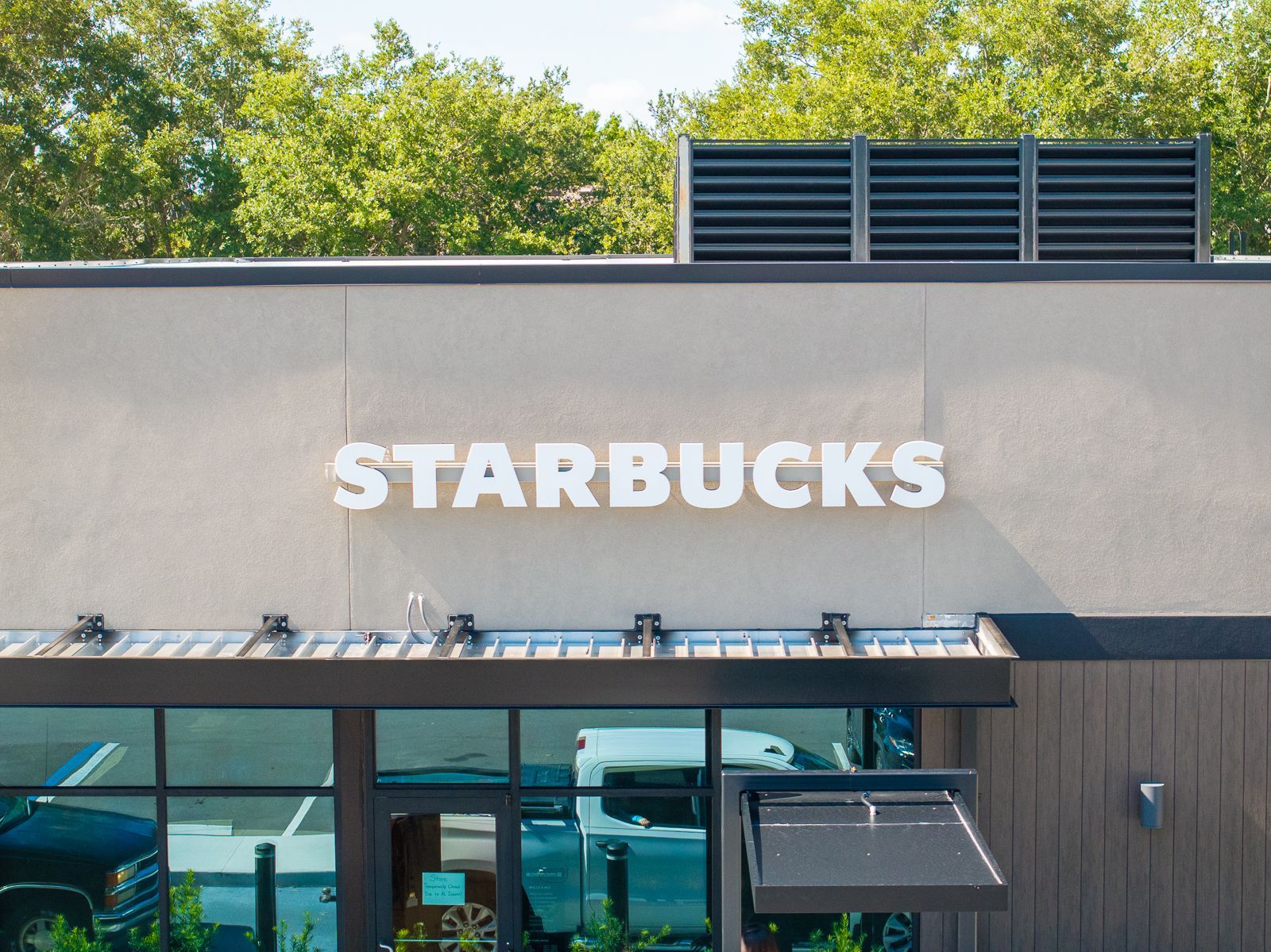 The front of a starbucks store with trees in the background