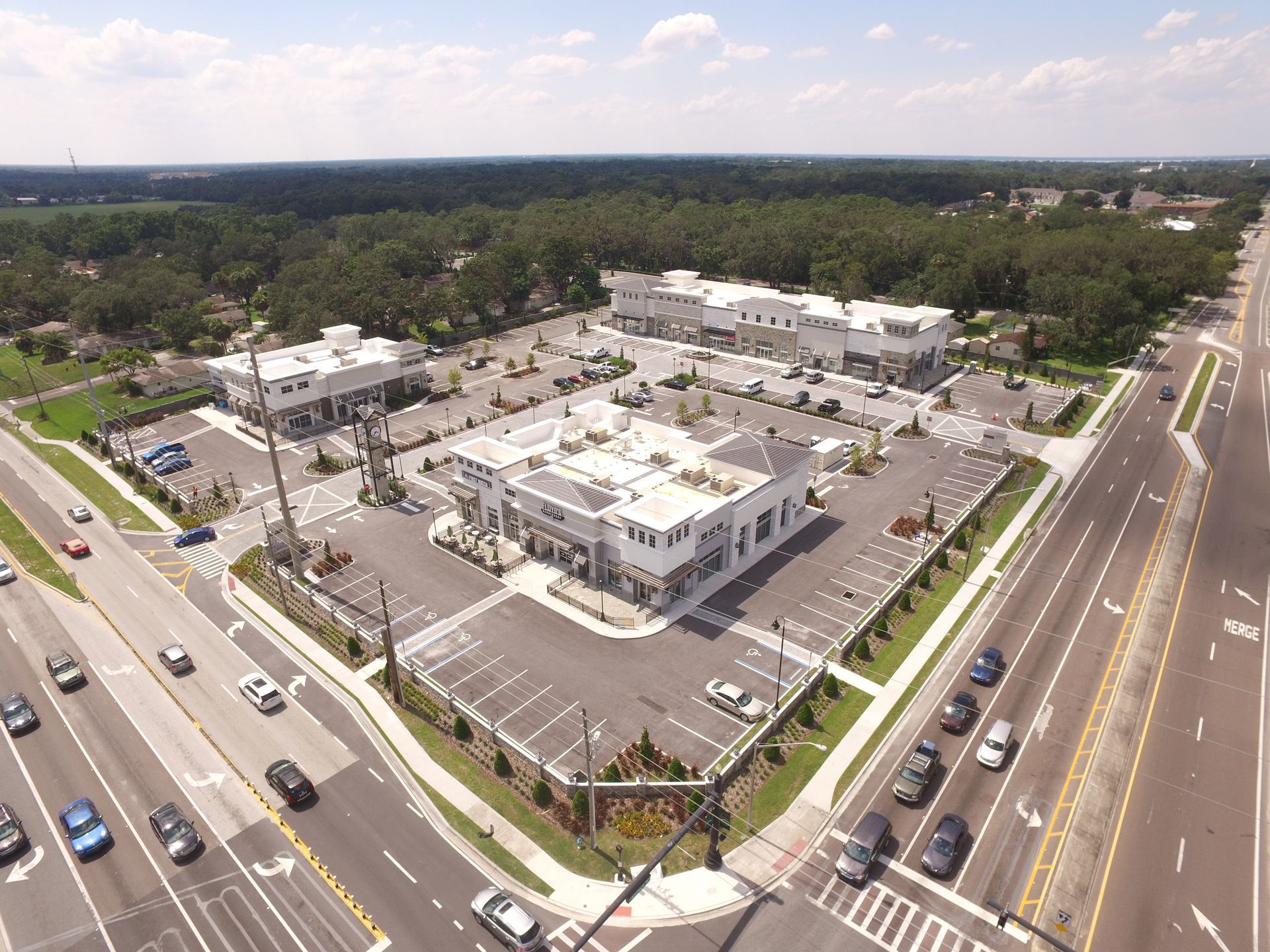 An aerial view of a parking lot surrounded by trees and a highway.