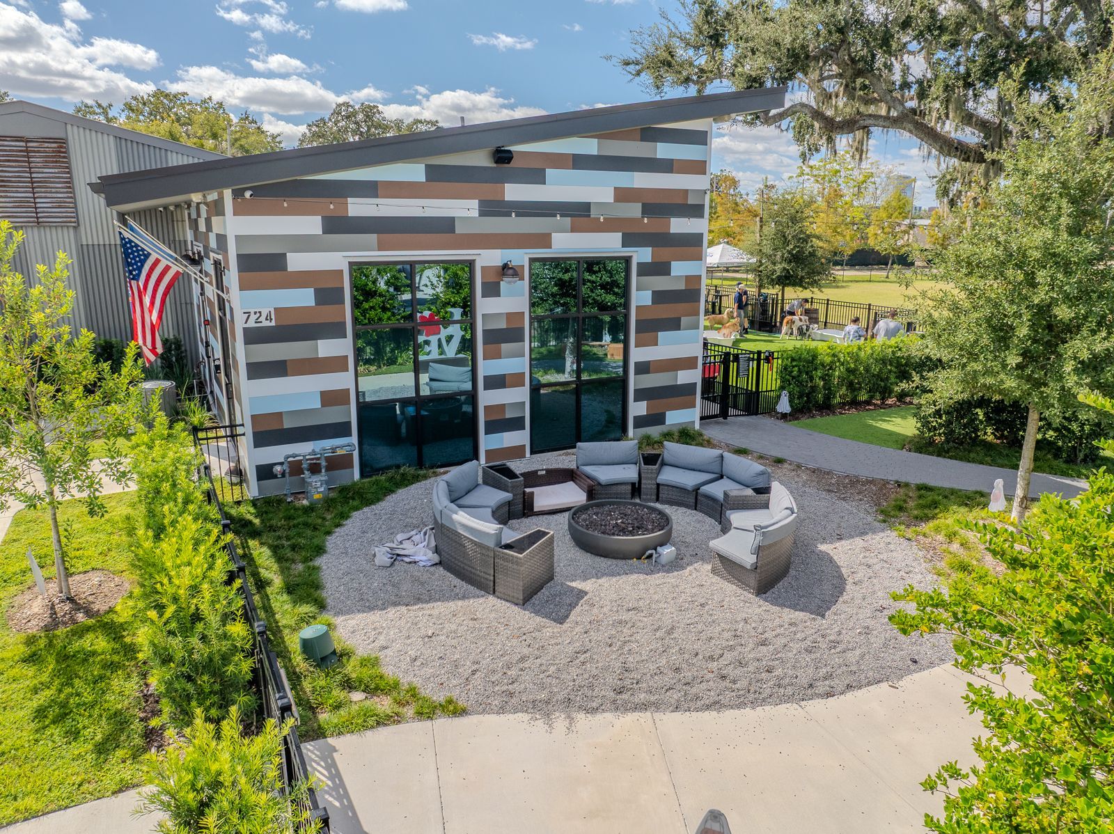 Modern building with multicolored siding, large windows, and outdoor seating around a fire pit.