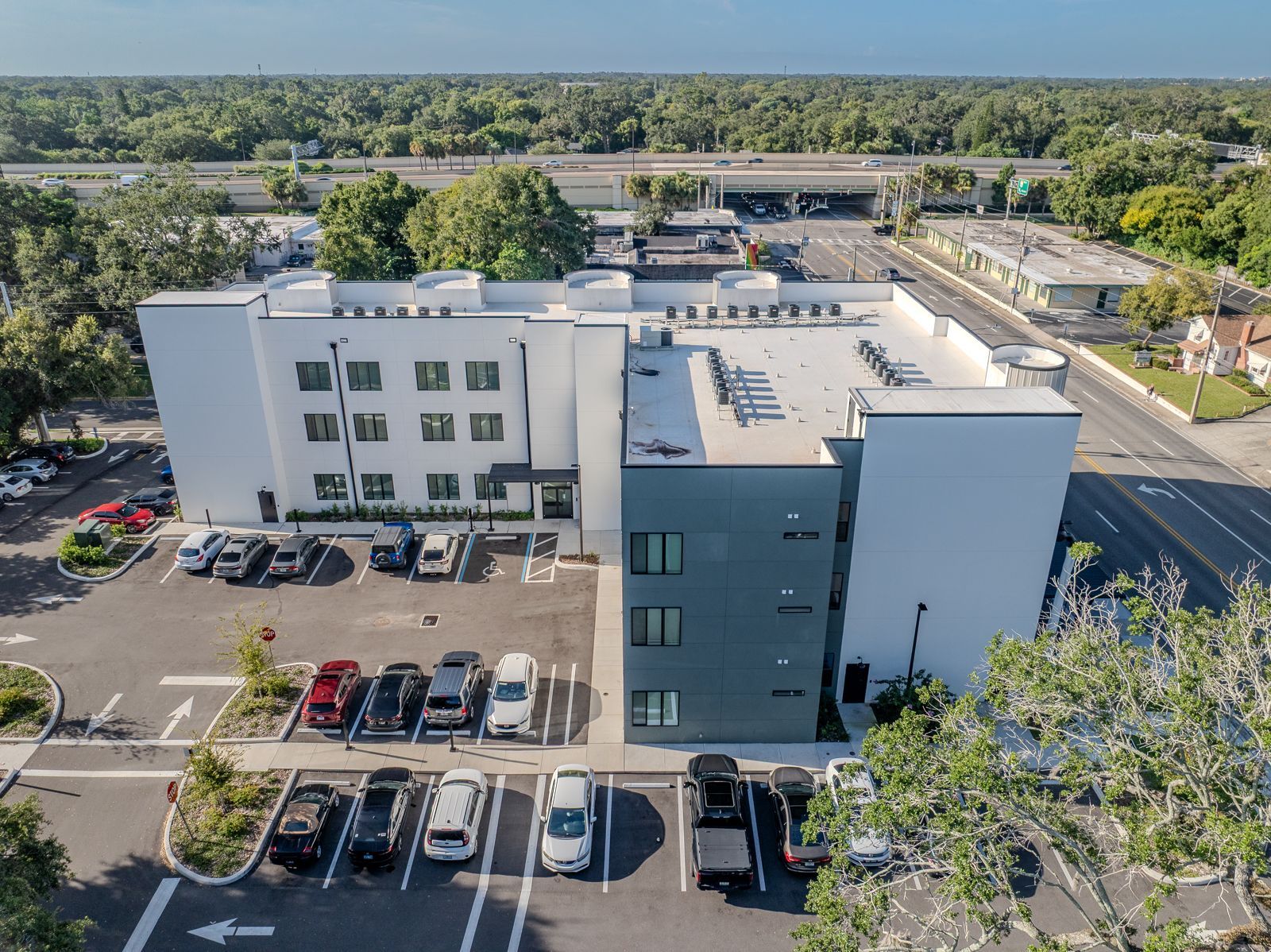 Modern white and teal building with parked cars in front.