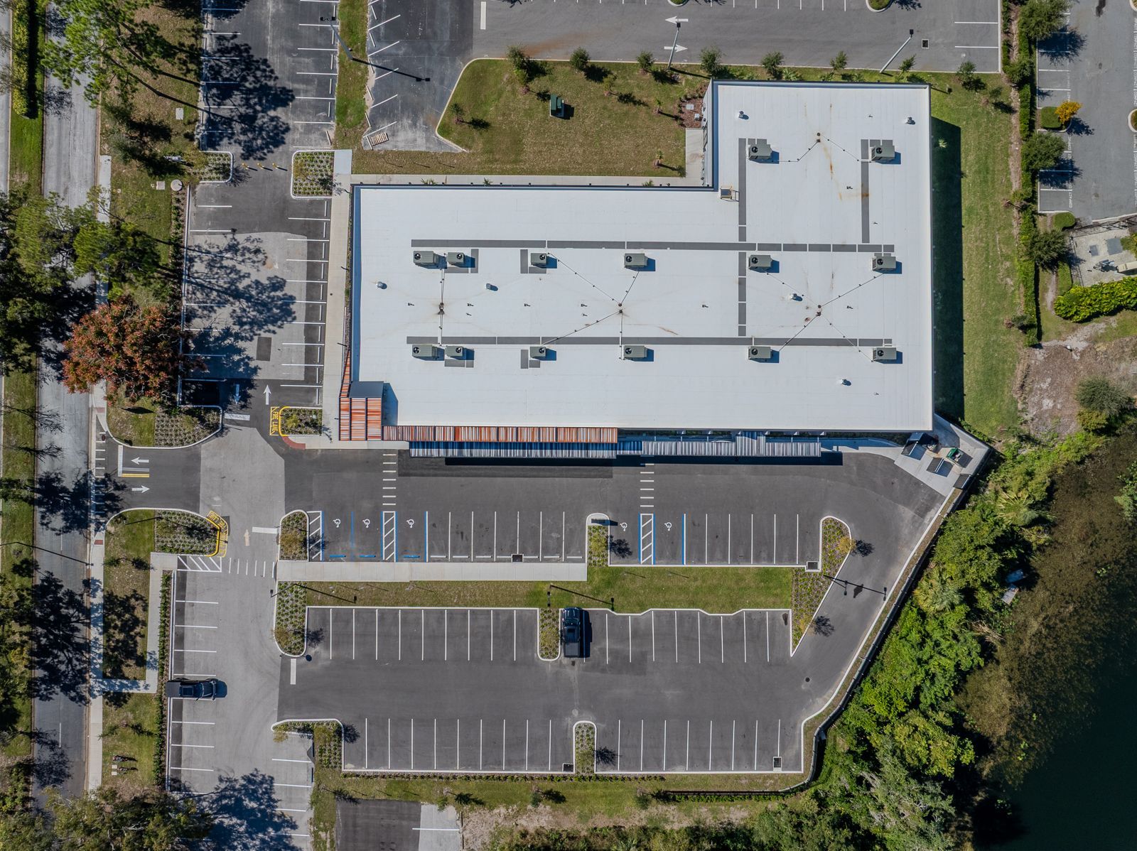 Overhead view of a building with a large parking lot and trees.