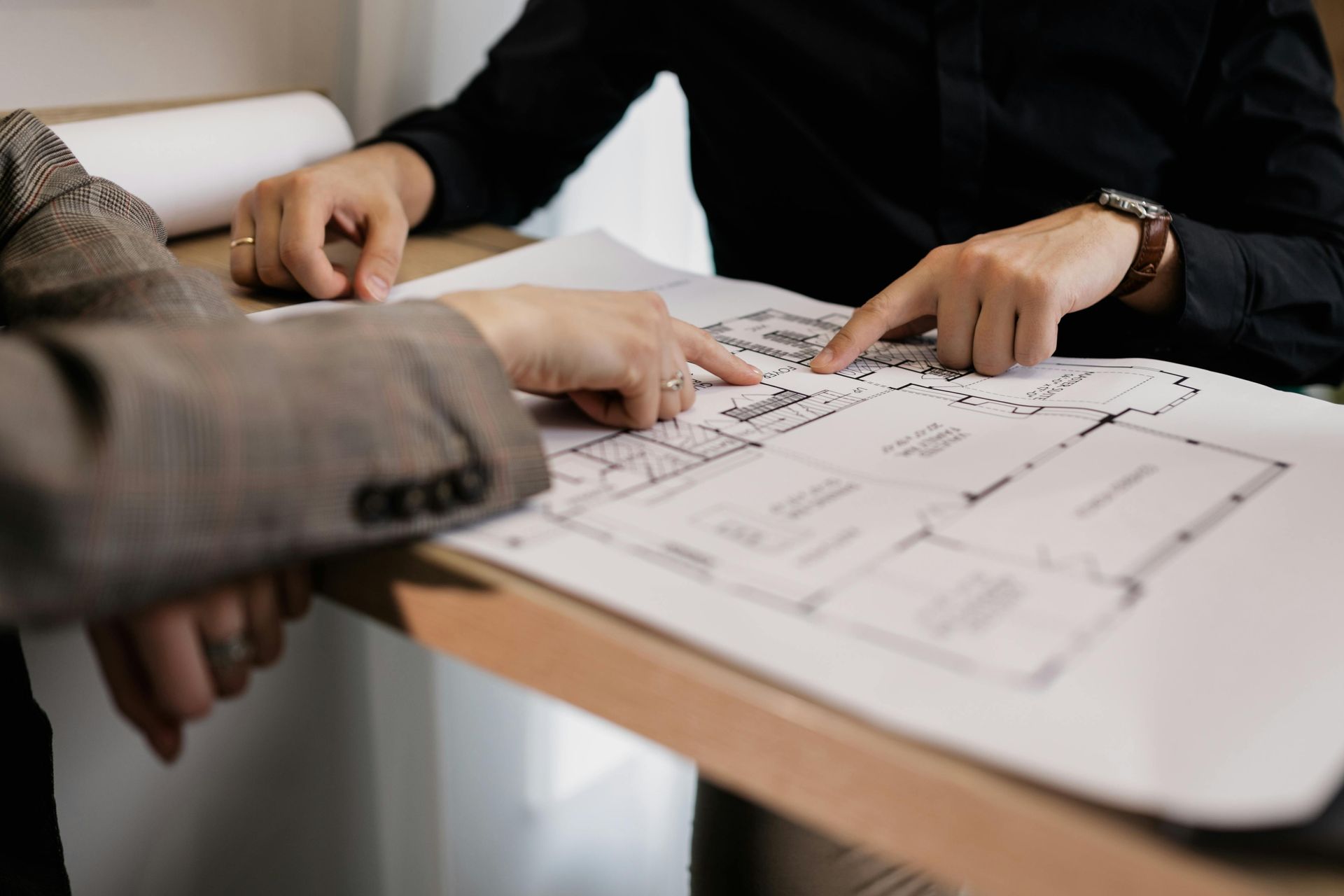 Two people are sitting at a table looking at a blueprint.