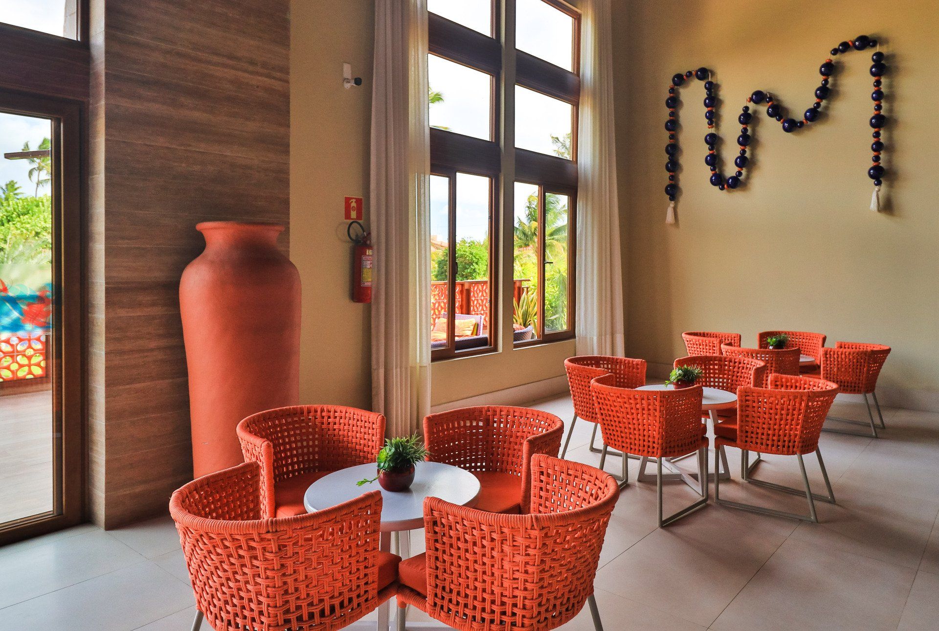 Uma sala com mesas e cadeiras e um grande vaso na parede