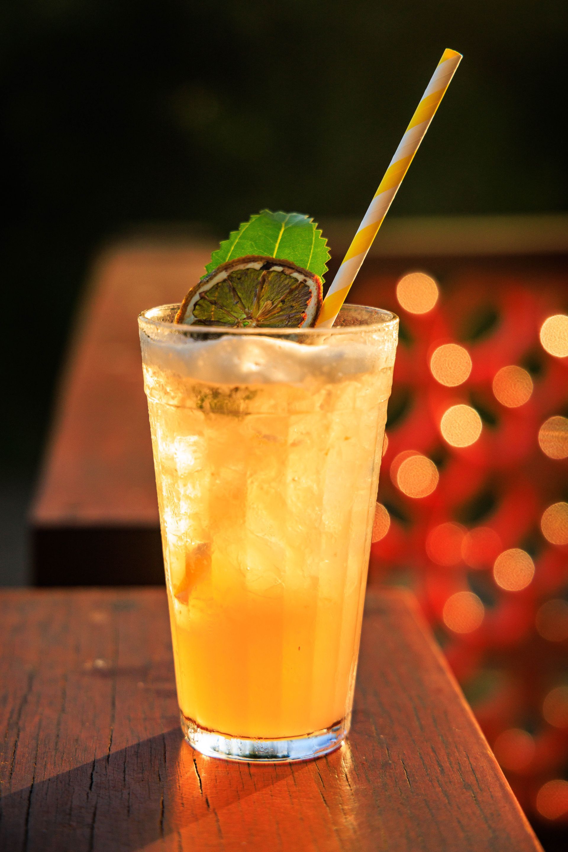 Uma bebida com um canudo está sobre uma mesa de madeira.