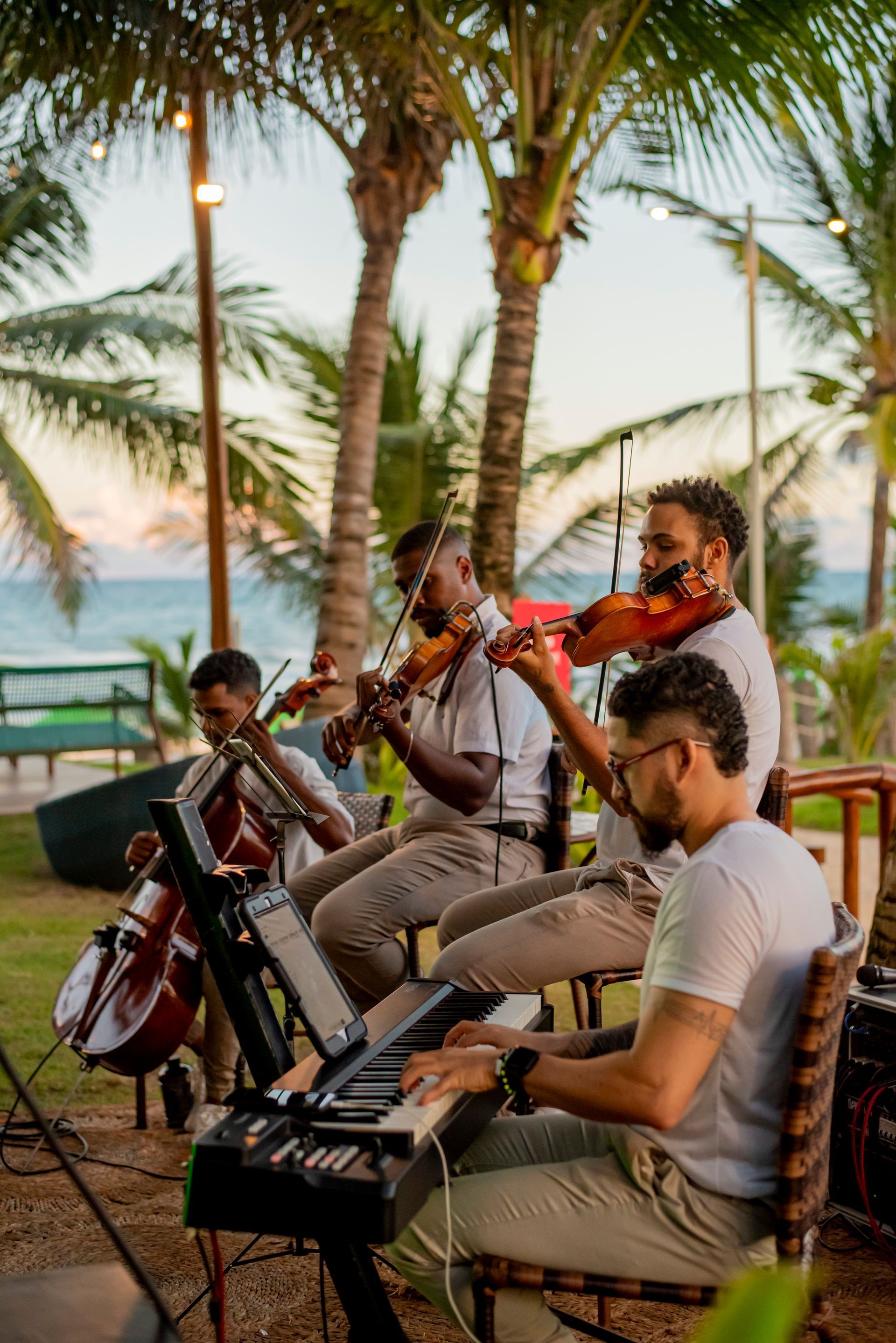 Um grupo de homens toca violino e violoncelo enquanto um homem toca teclado.
