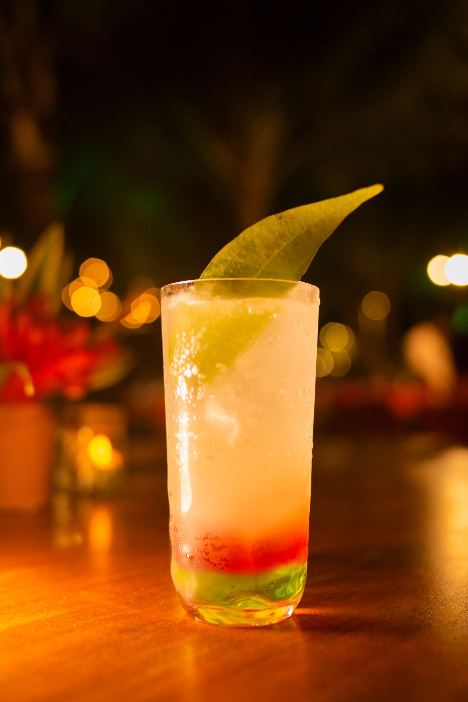Um close de um coquetel em um copo alto sobre uma mesa.