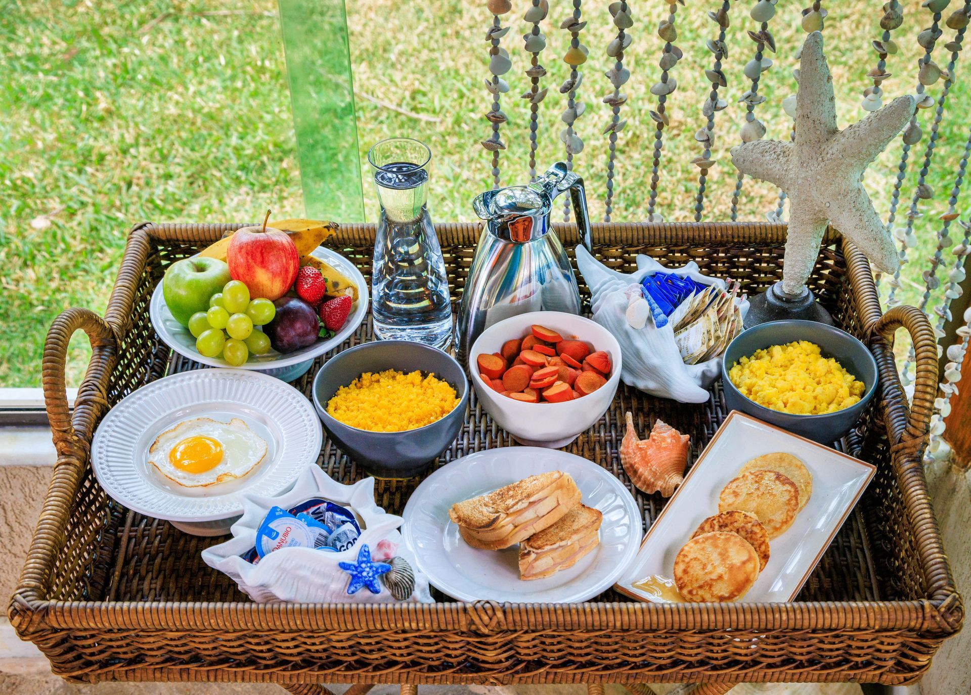 Uma bandeja de vime cheia de uma variedade de alimentos e bebidas.