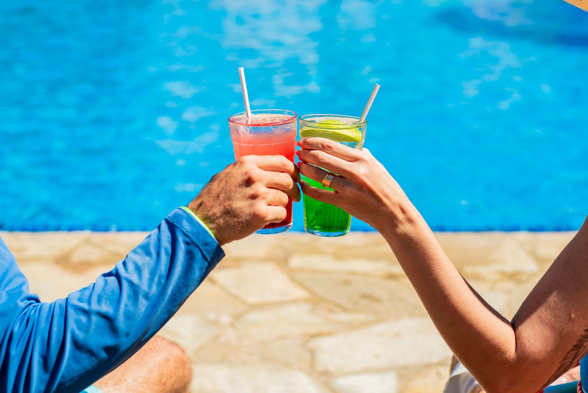 Um homem e uma mulher estão brindando com bebidas em uma piscina.