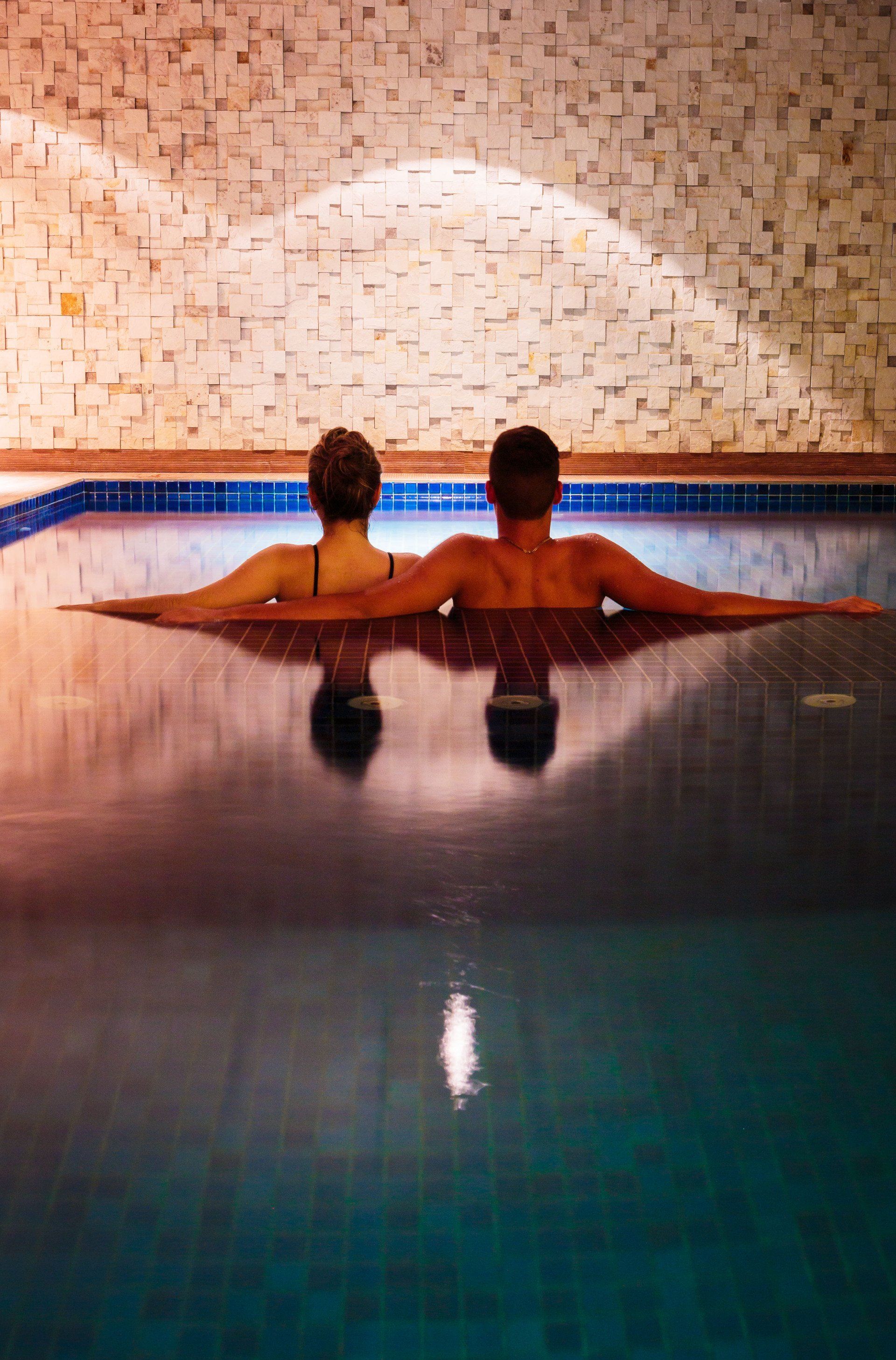 Um homem e uma mulher estão sentados em uma piscina.