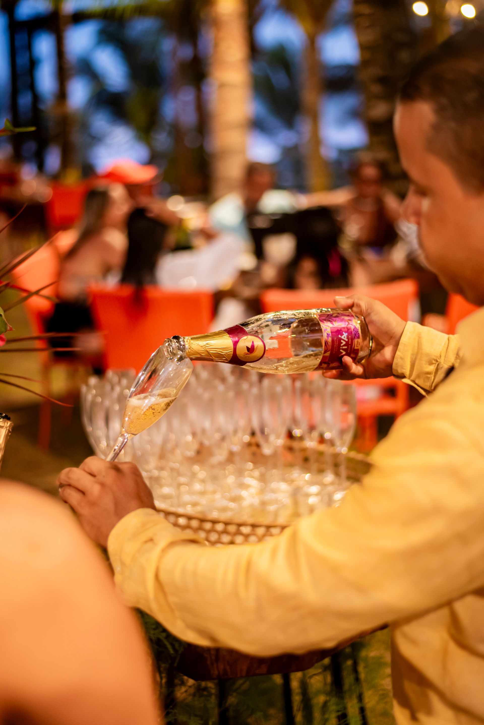 Um homem está servindo champanhe em uma taça em uma festa.