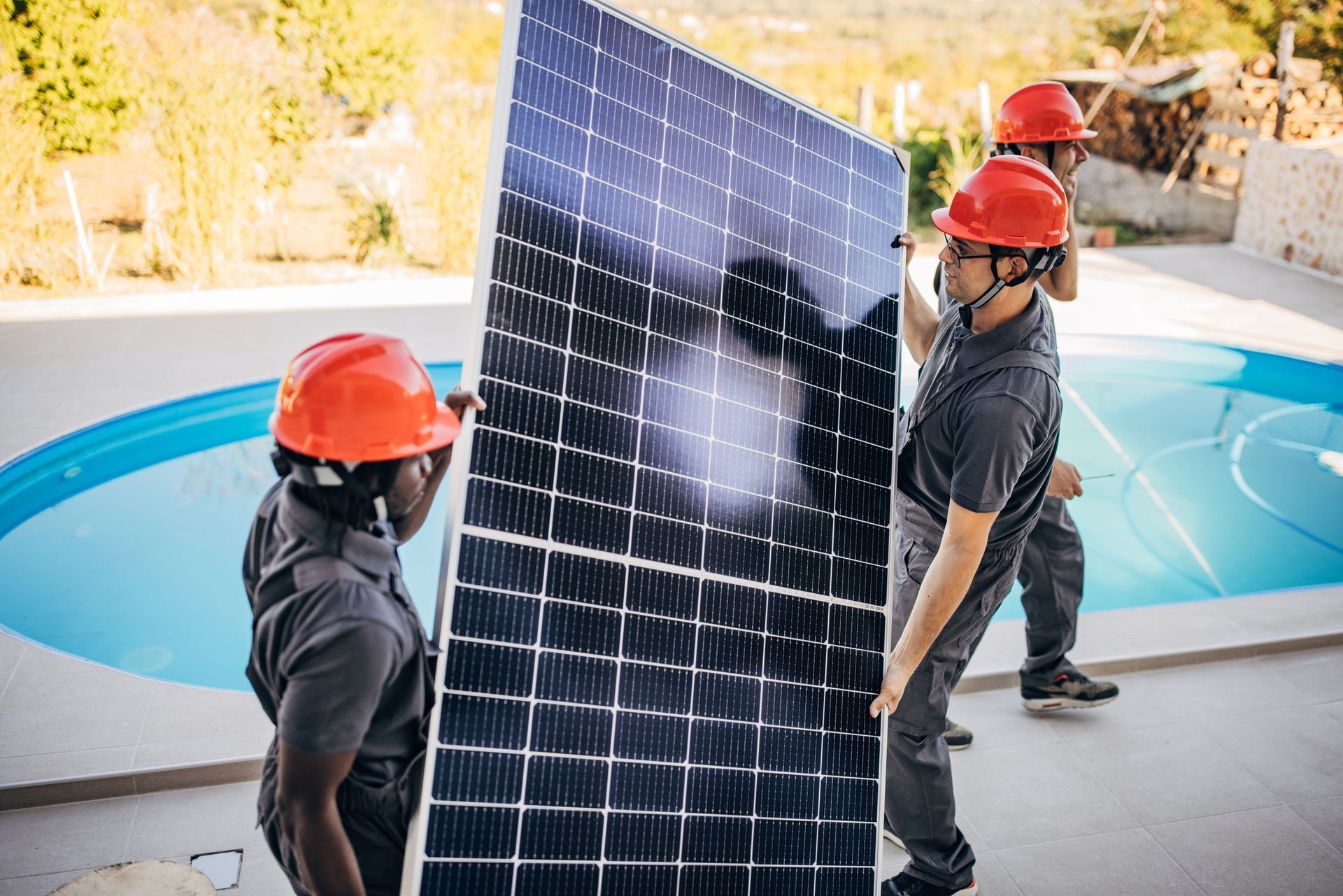 Two workers with protective, orange helmets, performing pool solar system service.