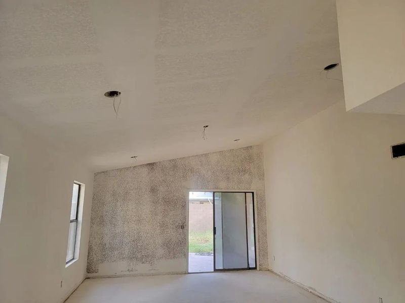 Interior view of a room with a sliding glass door, mold on a wall, and exposed wiring in the ceiling.