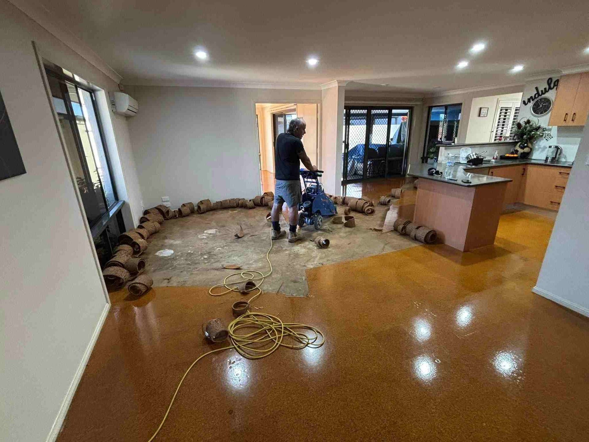A Person Sanding a Floor in A House with A Kitchen Visible in The Background — Gava Floor Centre in Kyogle, NSW