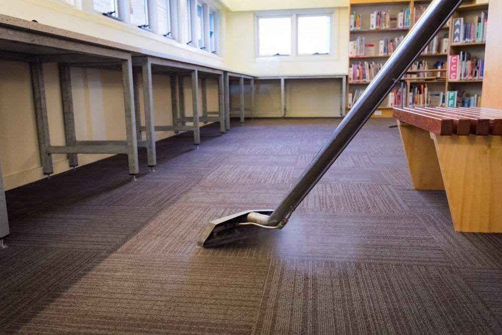 Vacuum Cleaner Cleaning a Brown Carpet in A Library, with Bookshelves and Tables — Gava Floor Centre in Casino, NSW