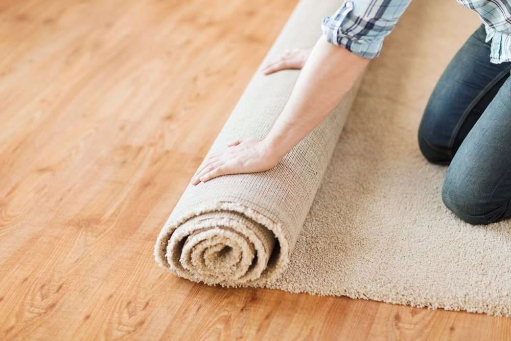 Person Kneeling, Rolling up A Tan Carpet on A Hardwood Floor — Gava Floor Centre In Goonellabah, NSW