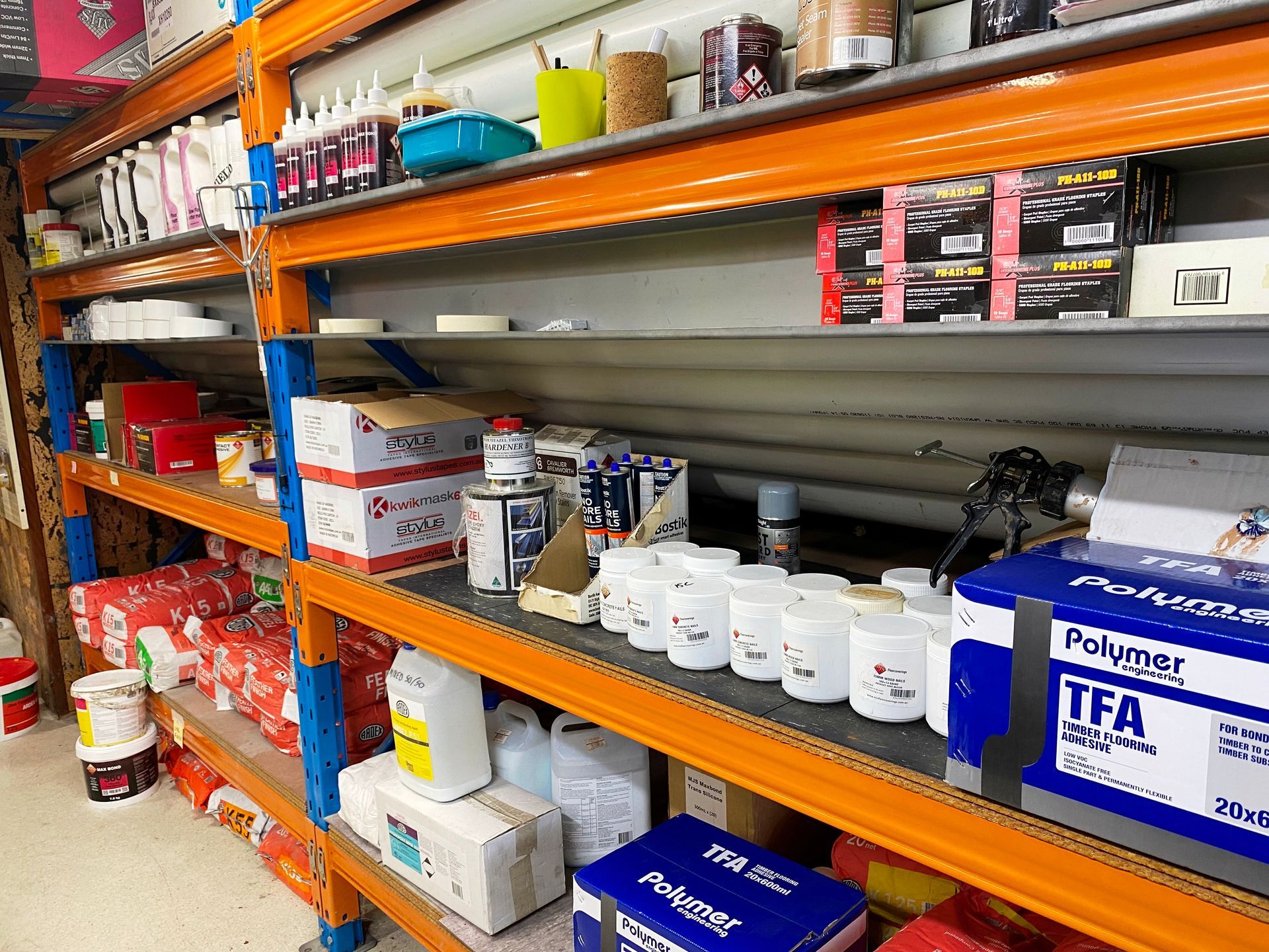 Shelves stocked with various paint and construction supplies inside a hardware store.