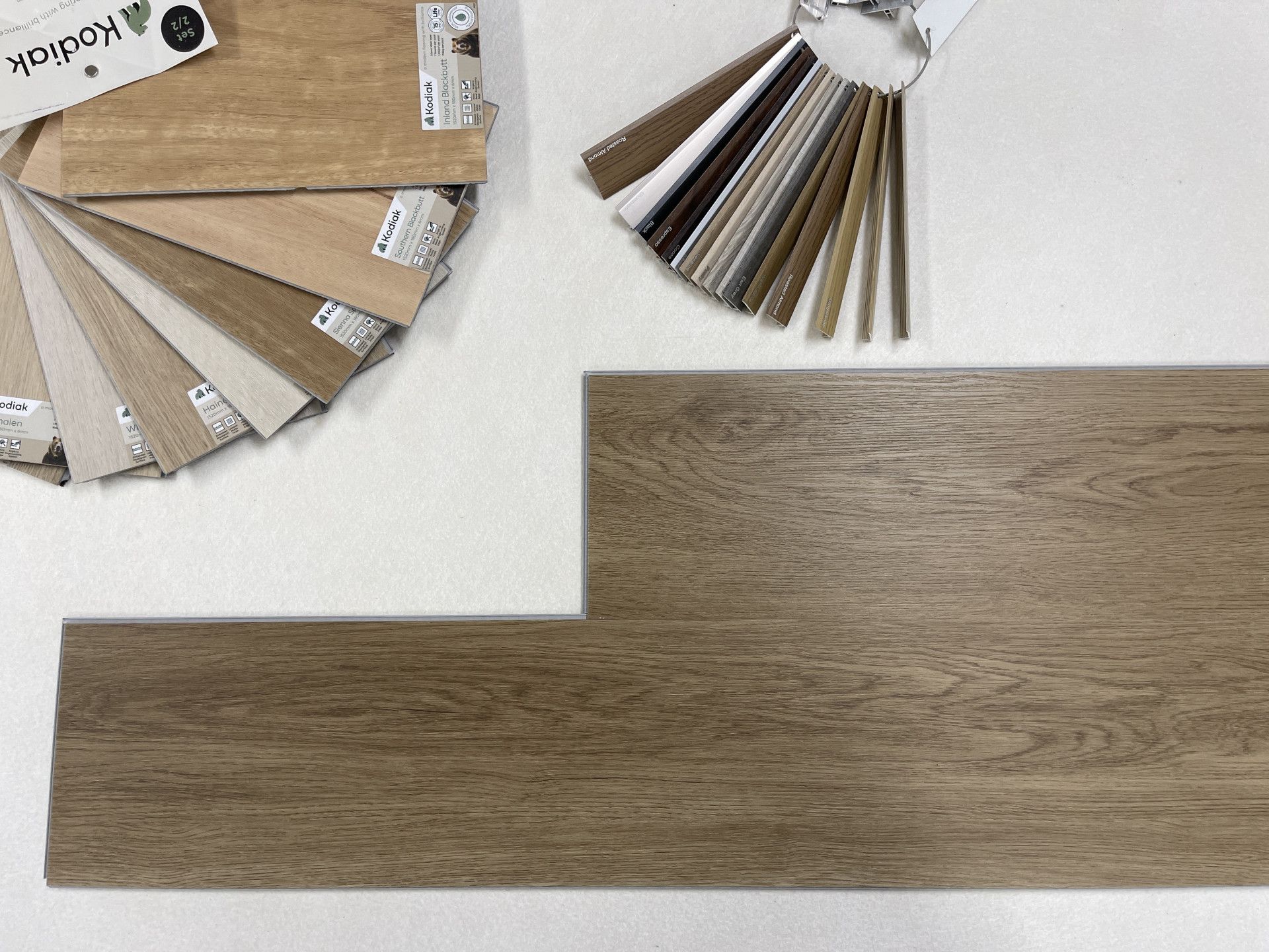 Wooden floor samples with color swatches on a white surface.