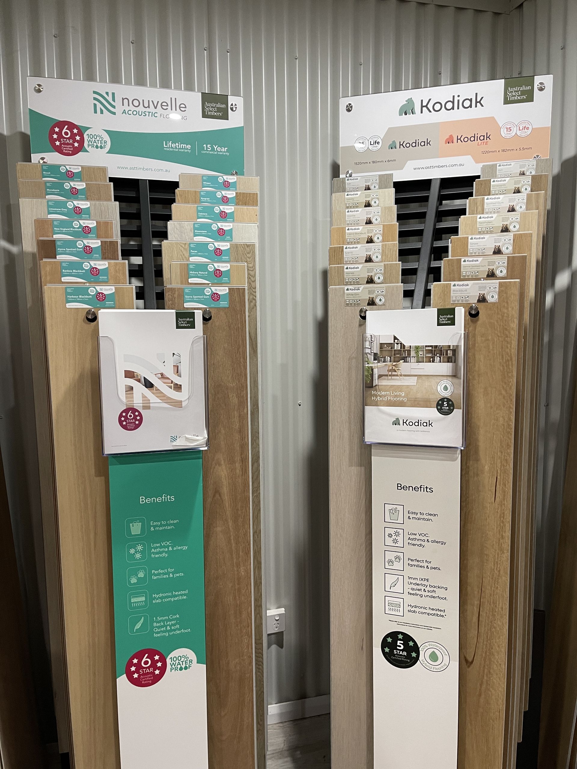 Two flooring sample displays against a corrugated wall. One has teal branding, the other beige.
