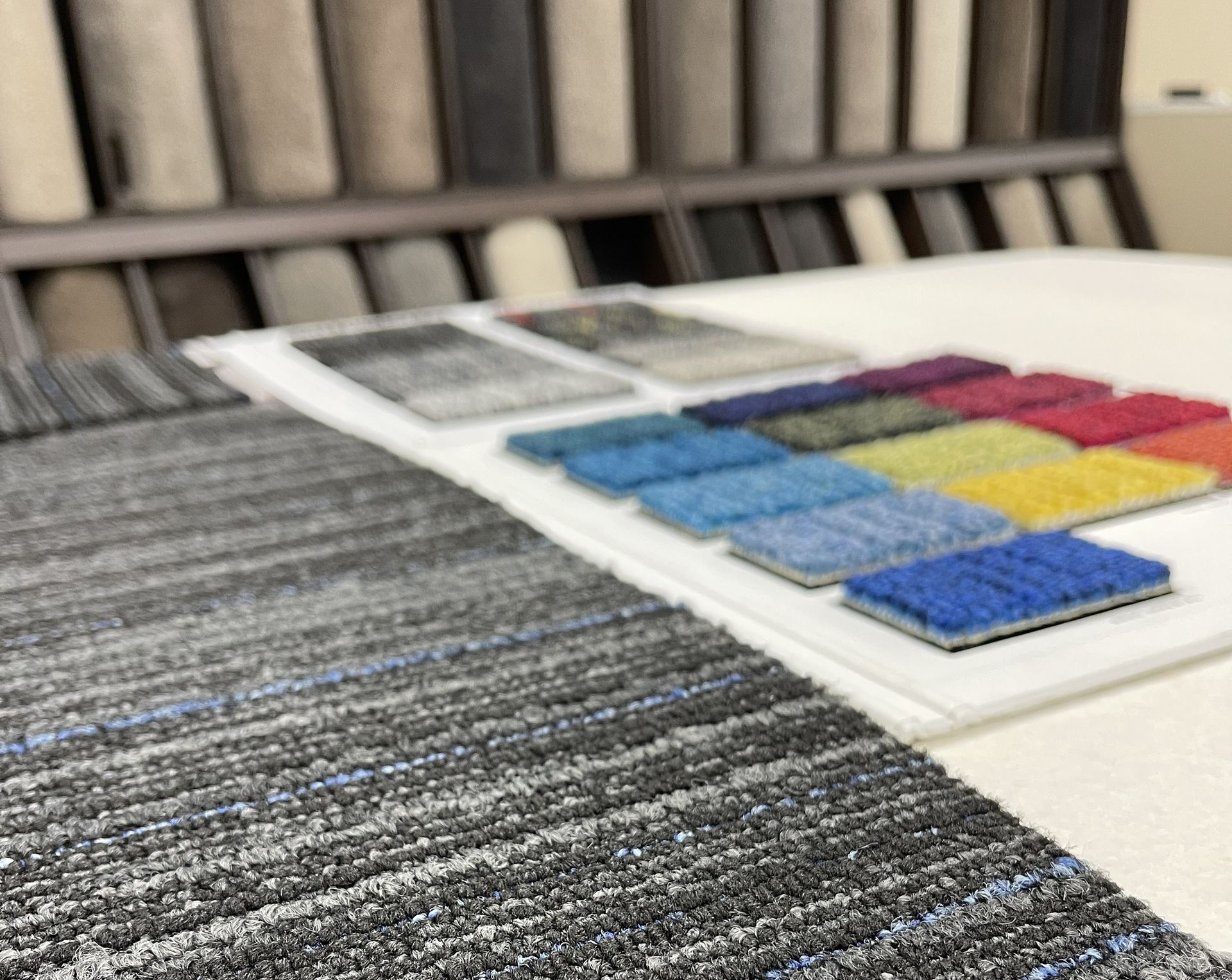 Close-up of carpet samples with color swatches on a display table in a store.