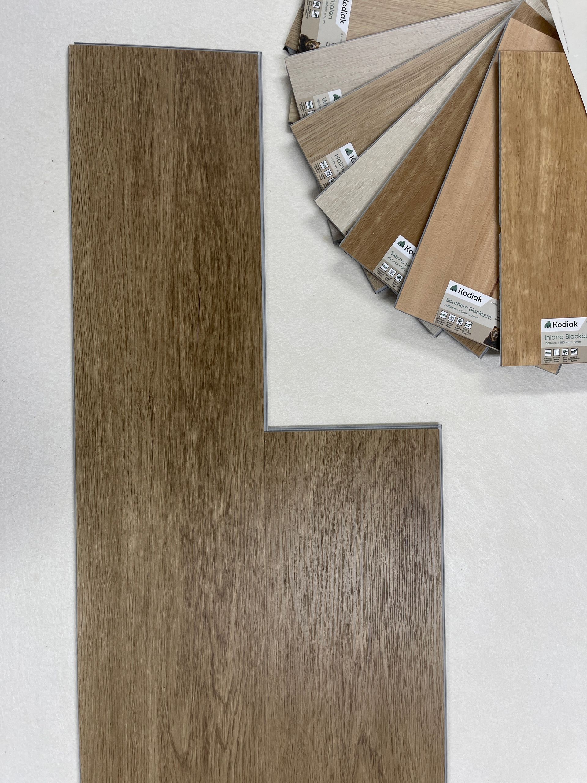 Wooden flooring samples; plank and sample swatches in various shades of brown and beige.