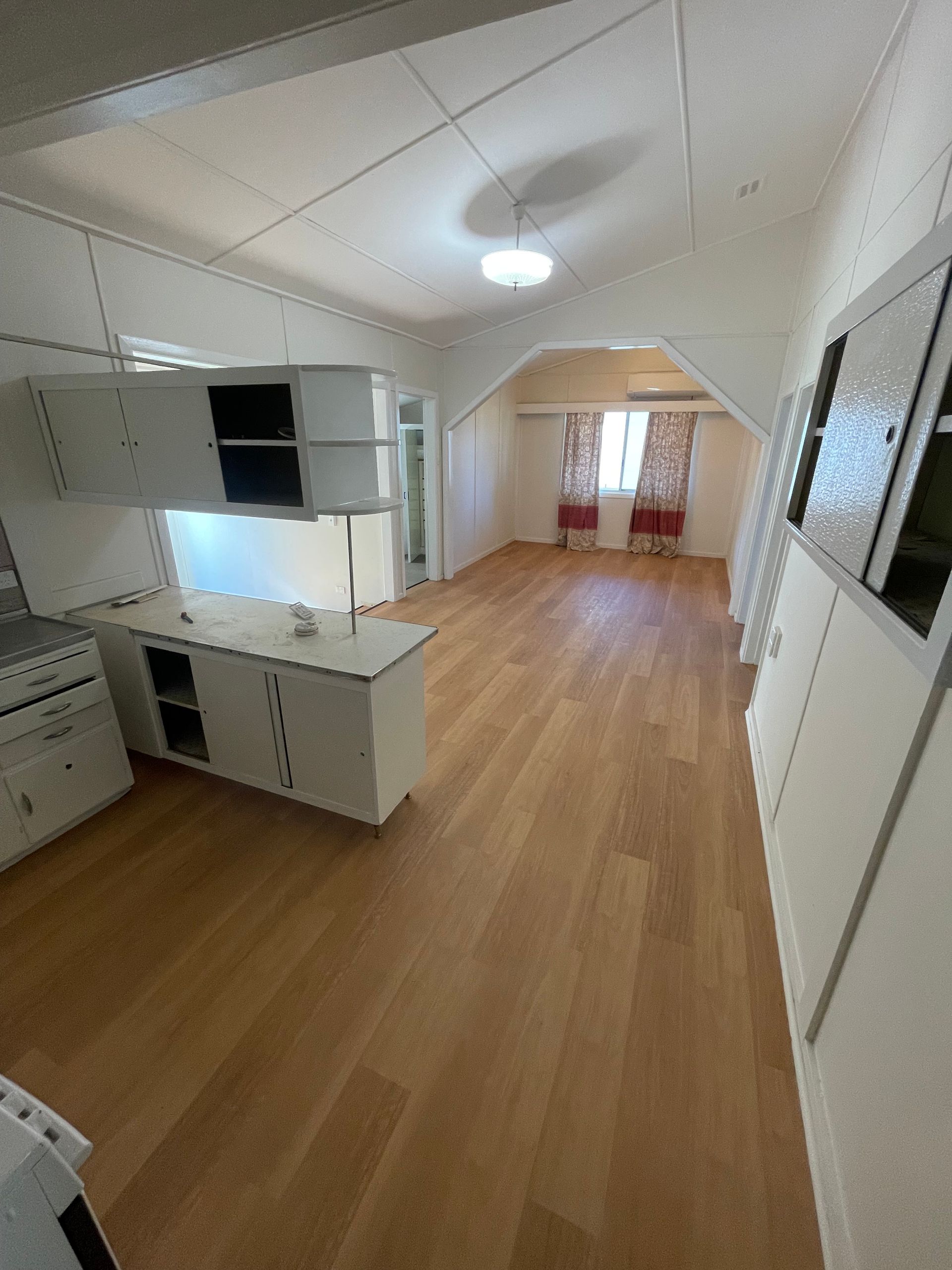 Interior view of a room with white cabinets, wooden floor, and arched ceiling.